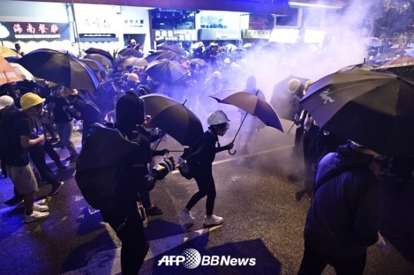 2019년 7월 28일 홍콩에서 논란이 되고 있는 송환 법안에 반대하는 시위 도중 시위대가 최루탄에 싸여 우산을 들고 있다. ⓒAFPBBNews
