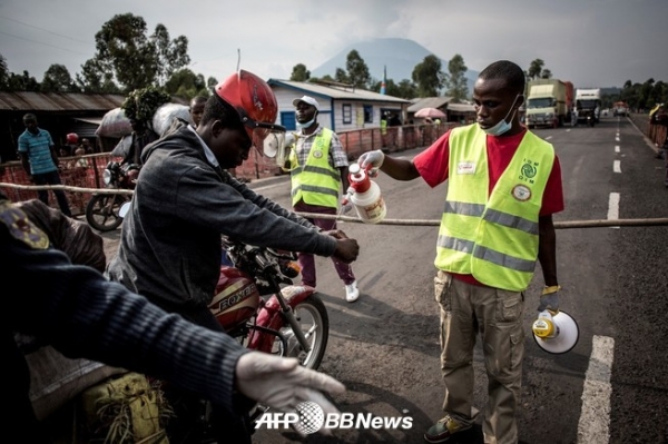 콩고 민주 공화국 고마에 계속 도로에 설치된 에볼라 검사소에 손을 세척하는 자전거 운전자 (2019 년 7 월 16 일 촬영)ⓒAFPBBNews
