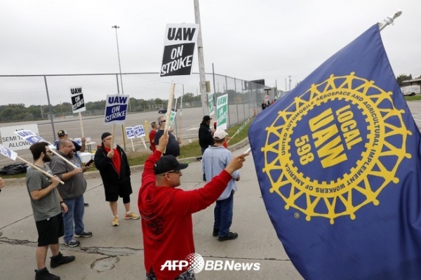 미국 미시간 주 플린트에 있는 미국 자동차 업체 제너럴 모터스 (GM) 공장 밖에서 전미 자동차 노조 (UAW)의 깃발을 들고 파업에 참가하는 직원 (2019 년 9 월 16 일 촬영). ⓒAFPBBNews