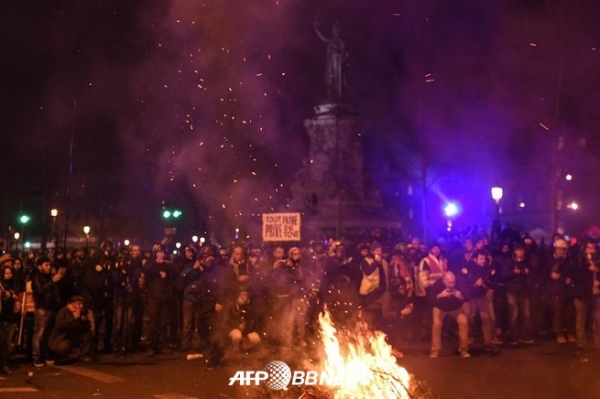 프랑스 파리 레퍼블릭크 광장에서 열린 연금 개혁에 항의하는 시위에서 불꽃 주위에 모인 사람들 ⓒAFPBBNews