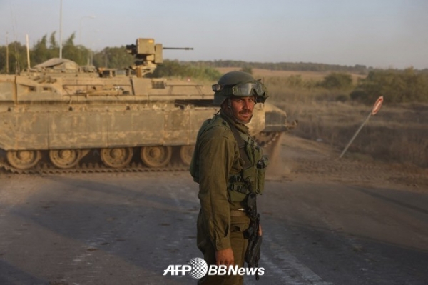 이스라엘과 팔레스타인 하마스 운동 간의 전투가 계속되는 가운데 2023년 10월 25일 가자지구 국경 스데롯 인근에서 이스라엘 군인이 장갑차 옆에 서 있다. ⓒAFPBBNews