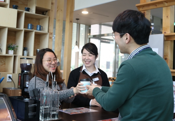 경기도 용인시 수지구 용인시다문화가족지원센터 1층에 위치한 카페 휴에서 근로자가 고객에게 커피를 제공하고 있는 모습 (사진출처 = 현대백화점 그룹)